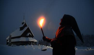 Olav Åsteson med fakkel utanfor Eidsborg stavkyrkje.